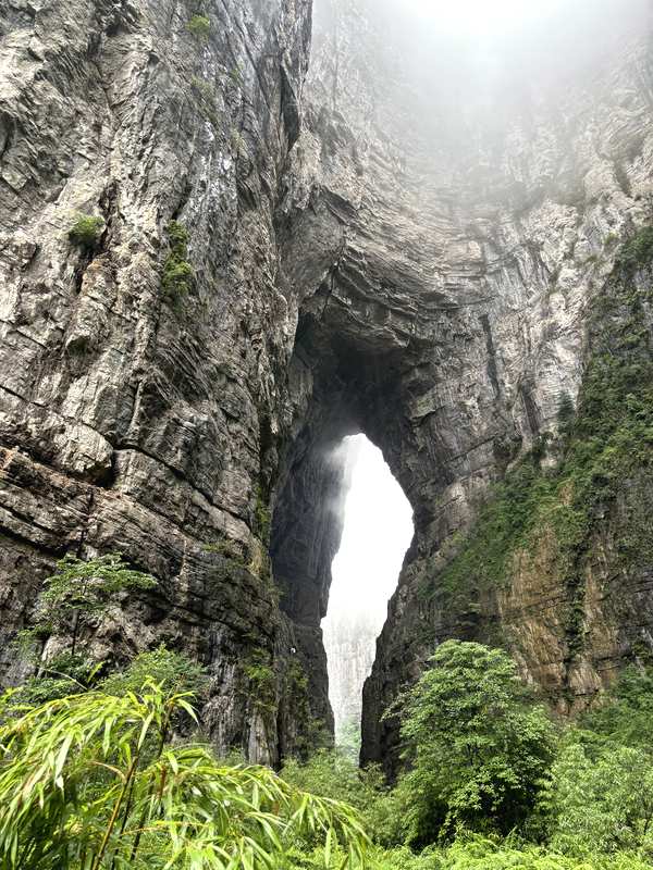 Dramatic low-angle view through the Three Natural Bridges stone arch, Wulong