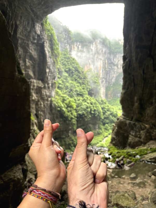 Hands framing the misty gorge view at Three Natural Bridges, Wulong