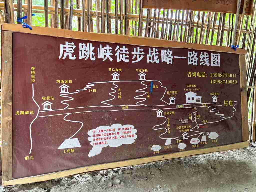 Large wooden trail map sign showing Tiger Leaping Gorge hiking route in Chinese with guesthouse locations, 28 bends, and Jinsha River marked