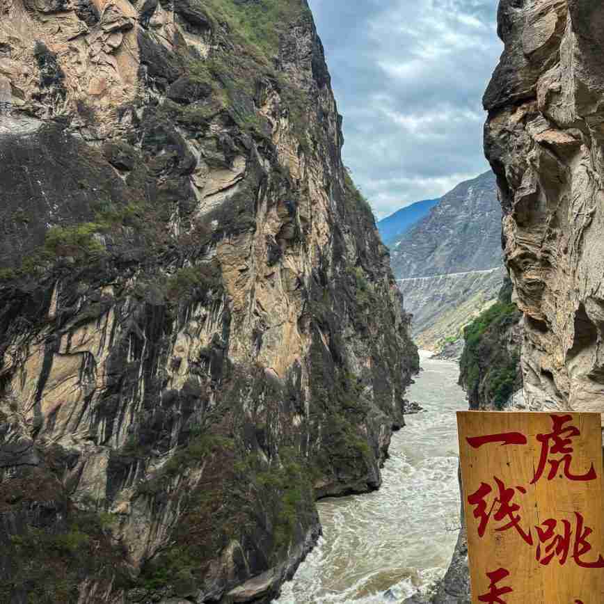 The famous 'Tiger Leaping' stone in the middle of the powerful Jinsha River at Tiger Leaping Gorge, a popular photo spot for visitors.