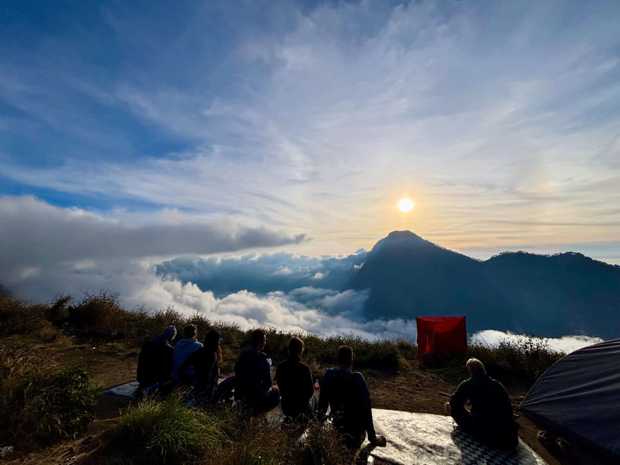 A breathtaking sunset over Mt Rinjani's peaks on Night Two of the trek, with colorful clouds streaking across the sky above silhouetted mountains.