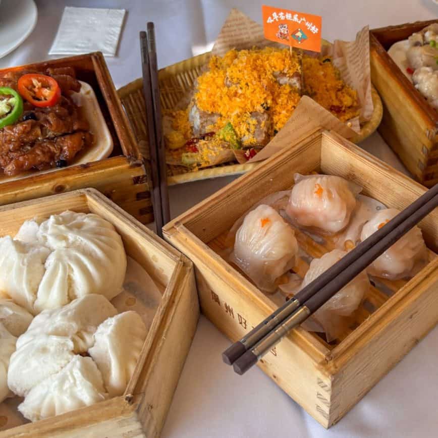A table filled with various dim sum including BBQ pork buns, chicken feet, and shrimp dumplings