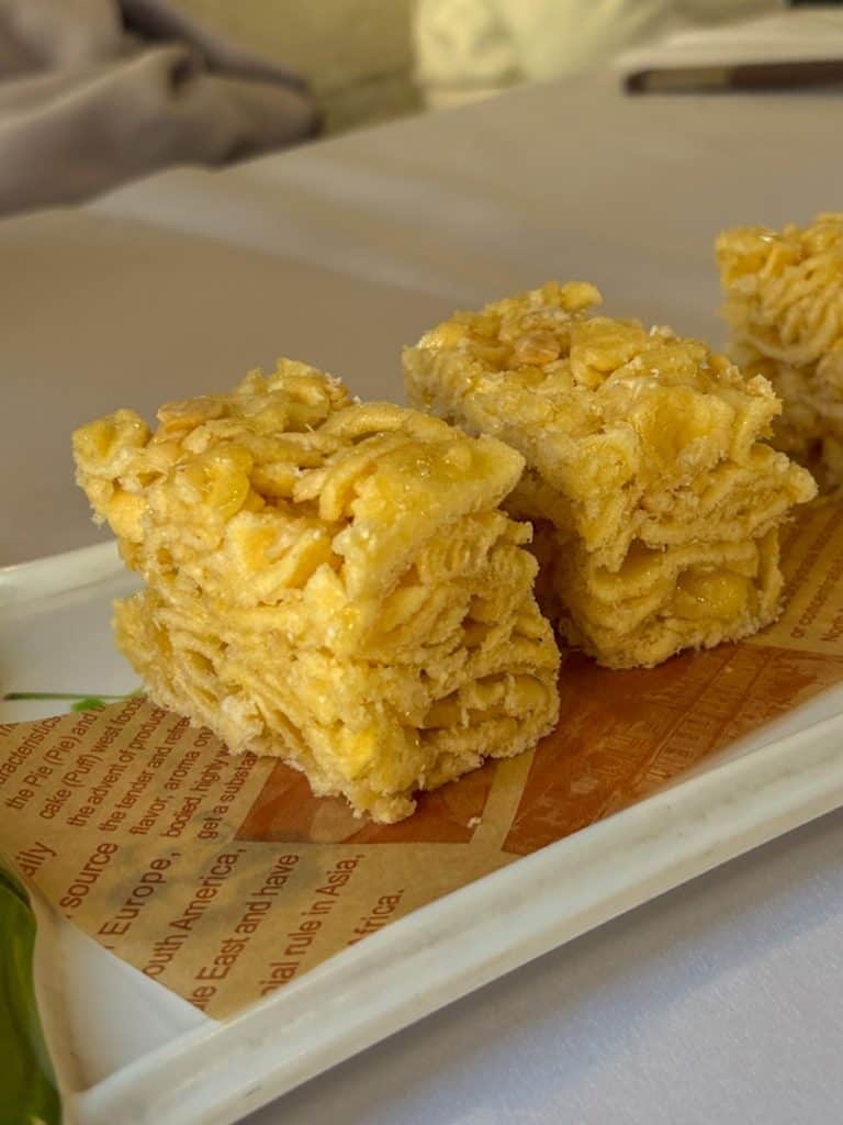 Three rectangular pieces of golden, porous honeycomb cake on a decorative plate.