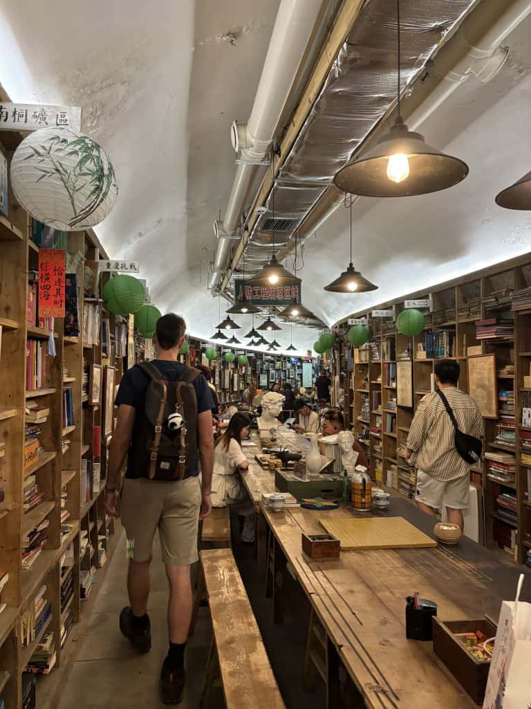 Interior of a unique bookstore in Chongqing built inside a repurposed underground air-raid shelter with long wooden tables and rows of books.