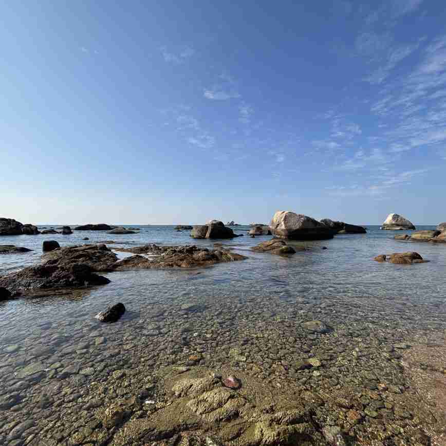 Beach with rocks and clear water, perfect for relaxing seaside holidays.