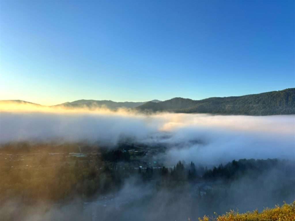 Thick morning fog rolling through the Hemu Village valley at sunrise, seen from Hadeng Viewing Platform, forested mountains in the background