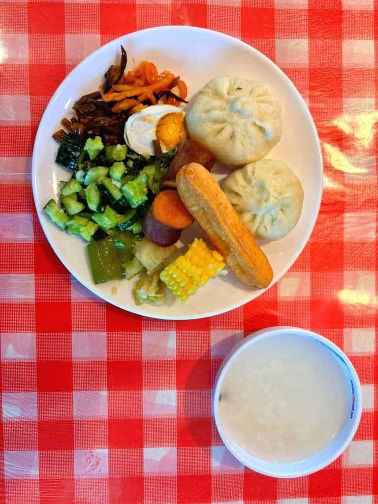 Buffet-style Chinese breakfast spread with tea eggs, congee, and cooked vegetables at a restaurant near our accommodation in Hemu Village