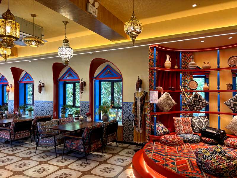 Ornate interior of a milk tea shop in Yining, with red archways and patterned cushions
