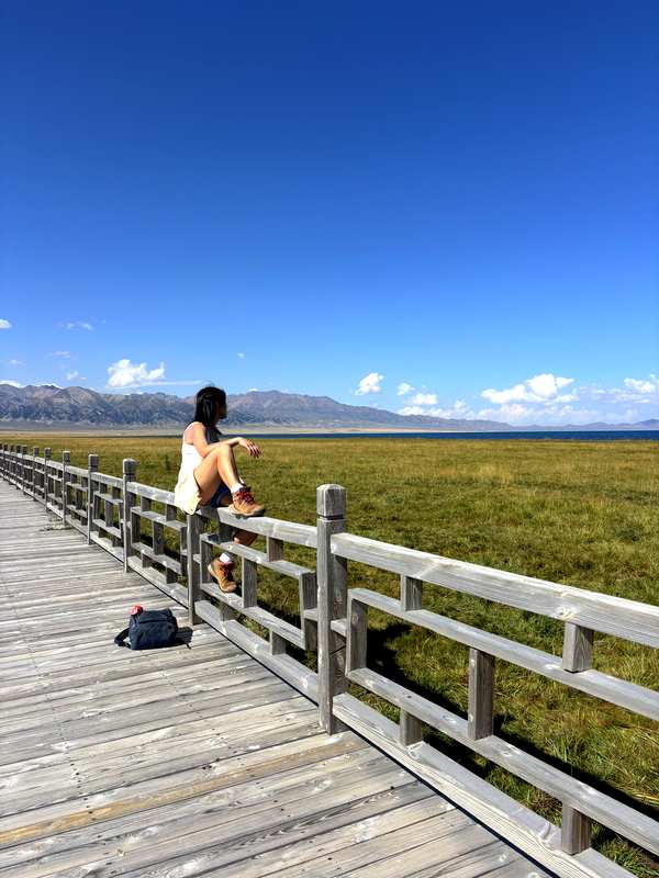 Sitting on the boardwalk railing at West Sea Grassland, Sayram Lake, Xinjiang